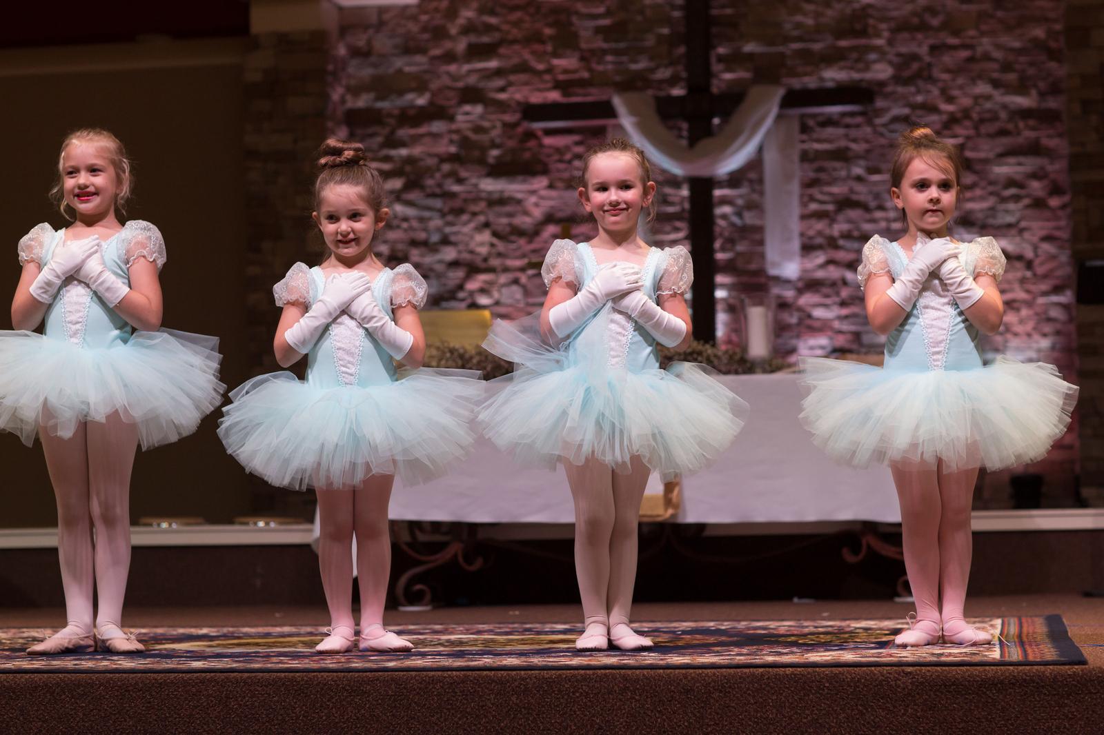 Young dancers in pink tutus performing on stage at a recital
