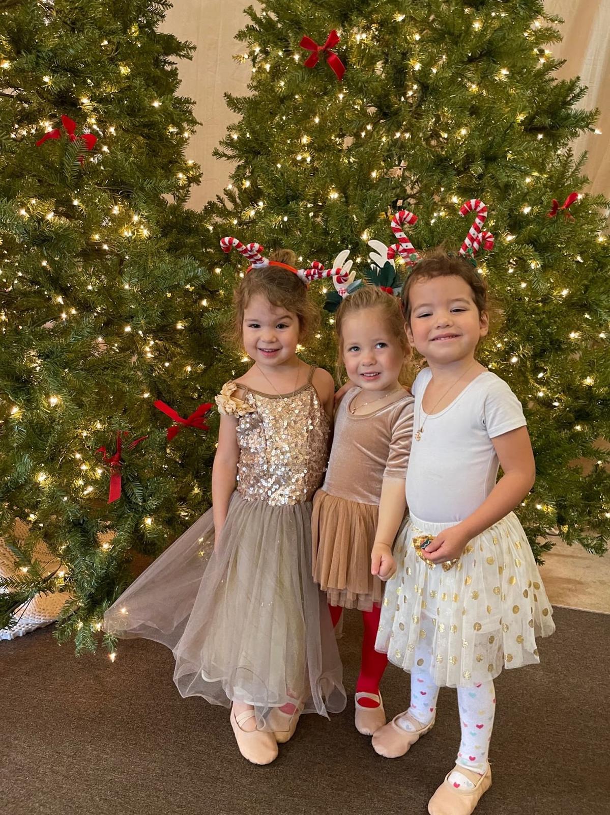 Three dancers in festive dresses in front of the Christmas tree at Watch Me Week