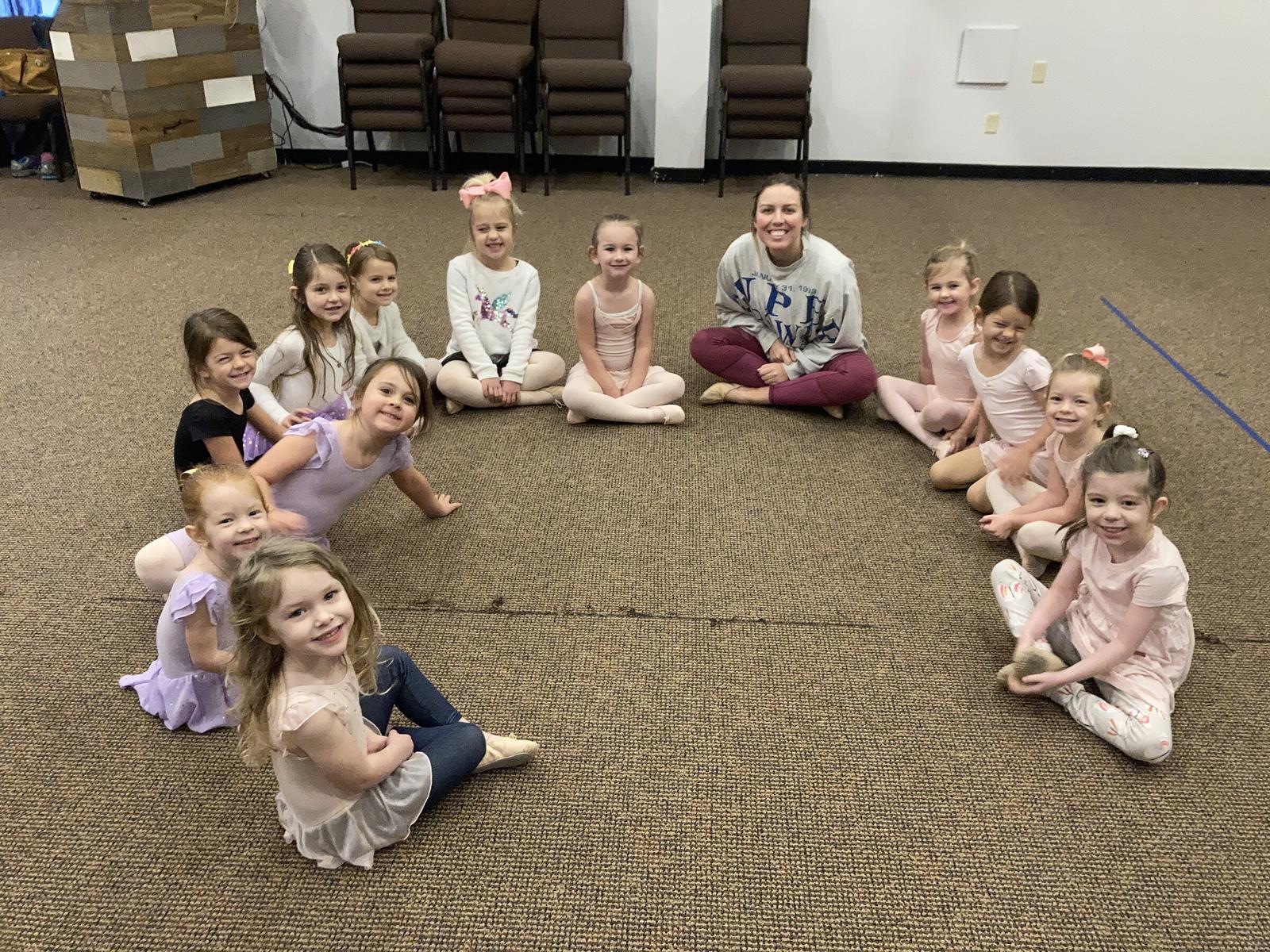 A whole class sitting in a wide circle on the Big Room floor with their teacher